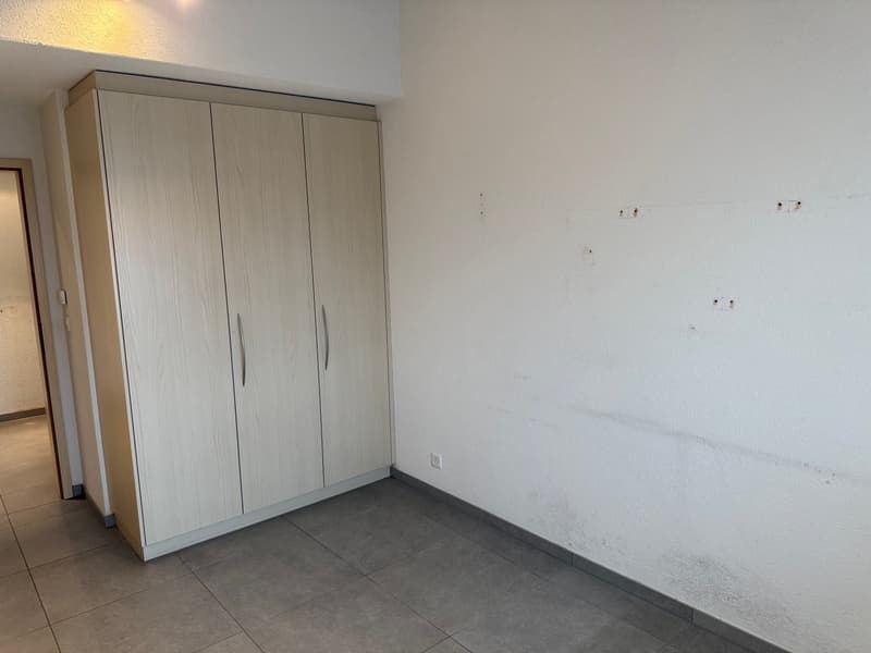an empty room with a wooden cupboard and white wall