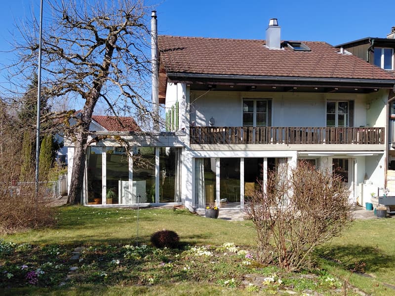 2 story house, white walls, brown roof, large glass windows, terrace, garden