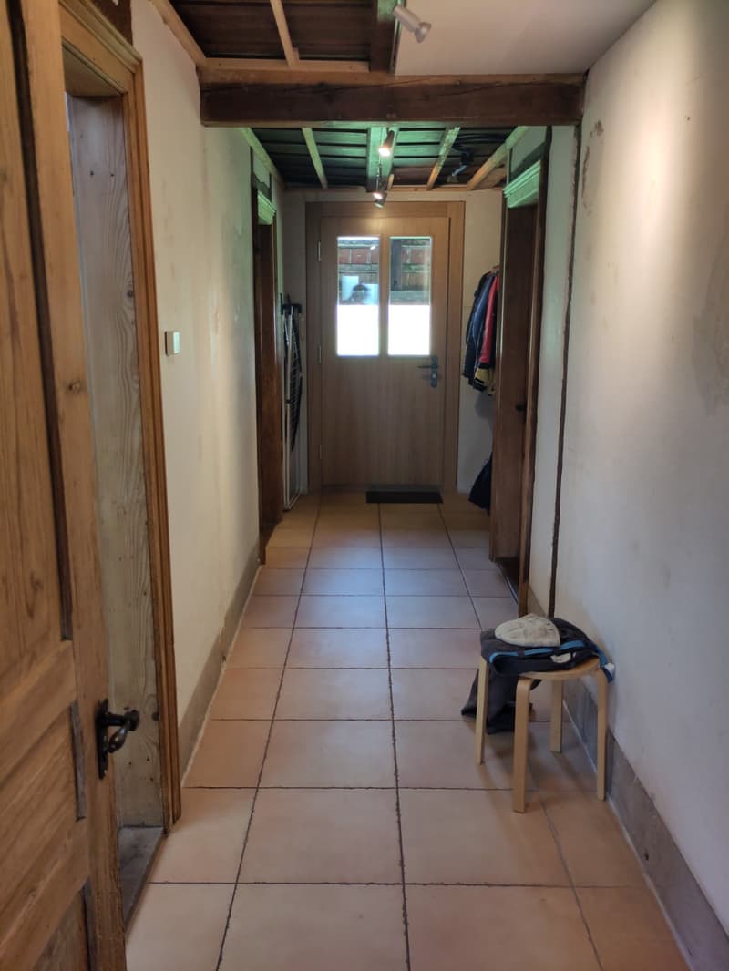 tiled floor, wooden doors, wooden stool, clothes hanging on the wall, wooden beams on the ceiling