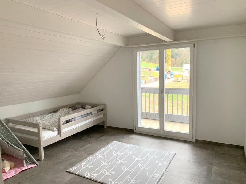 A bed, rug, and sliding glass doors that lead to a balcony.