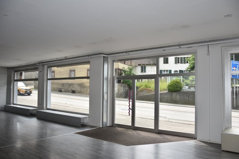 an empty room, double doors, glass windows, wooden floor, two benches, and a small white stool.