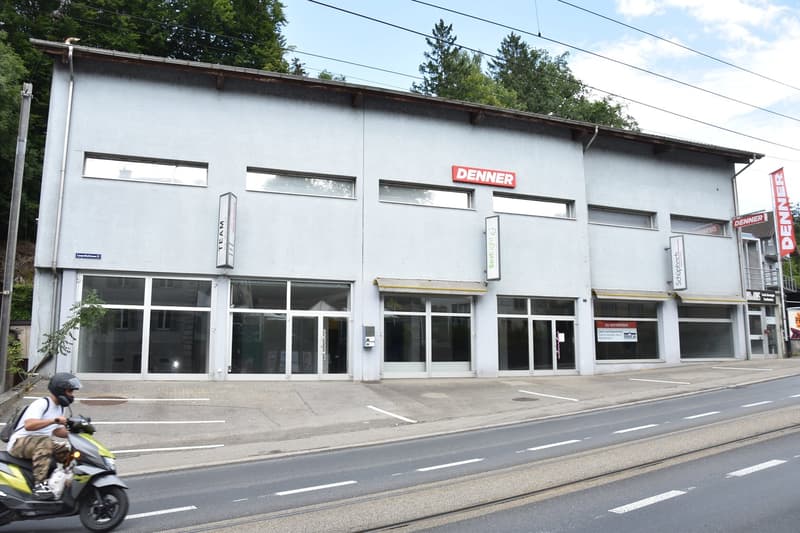 2 story building, white exterior, glass doors, windows, red signage reading DENNNER, parked scooter on the side of the road
