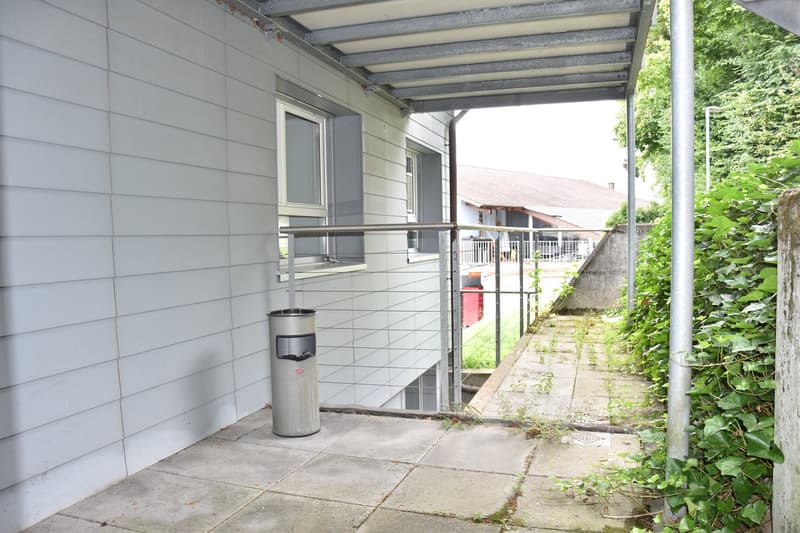 Covered outdoor area, trash bin, metal railing, and white tile floor.