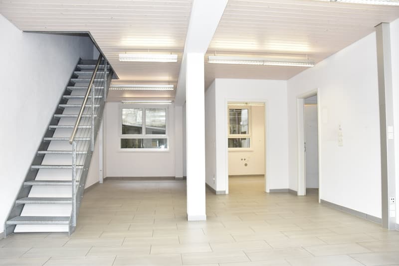 empty room with white walls, wooden floors, a staircase to the second floor, windows
