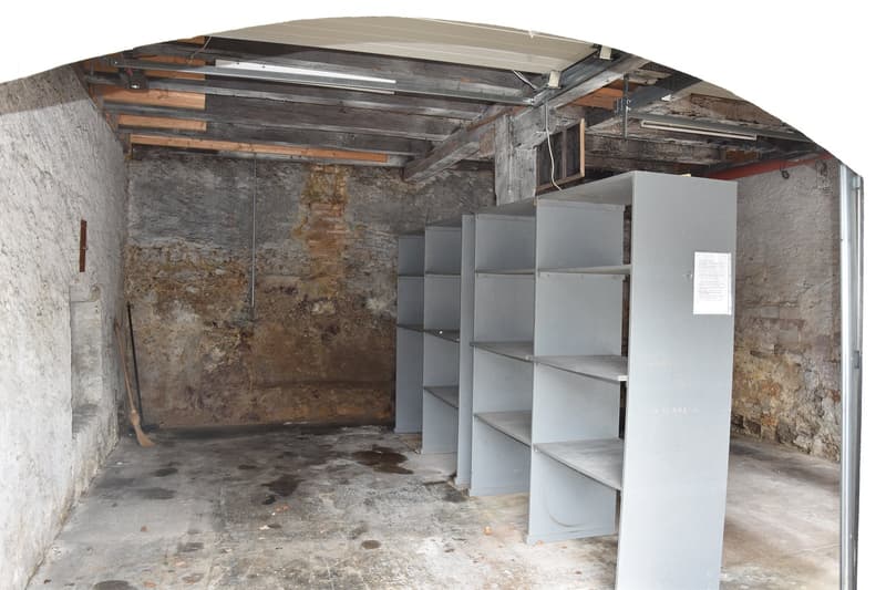 empty storage room with exposed brick walls, wooden shelves, dirty floor