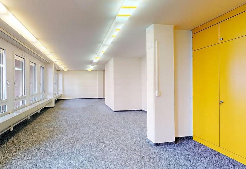 Empty room, concrete floor, yellow doors, white walls, ceiling lights, windows