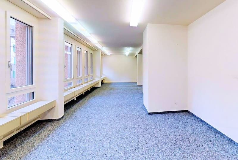 Empty room, white walls, blue carpet, windows, benches, lamps