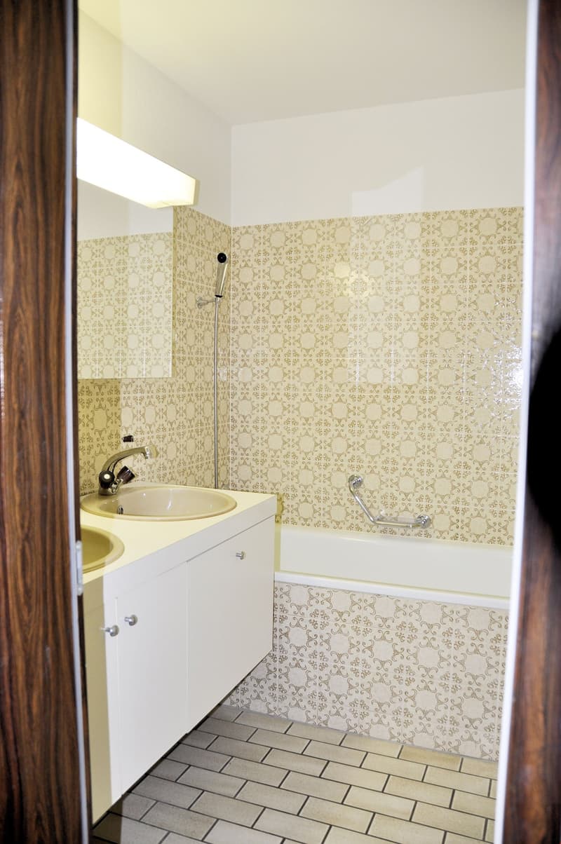 Bathroom with two sinks, bathtub, and patterned tiles