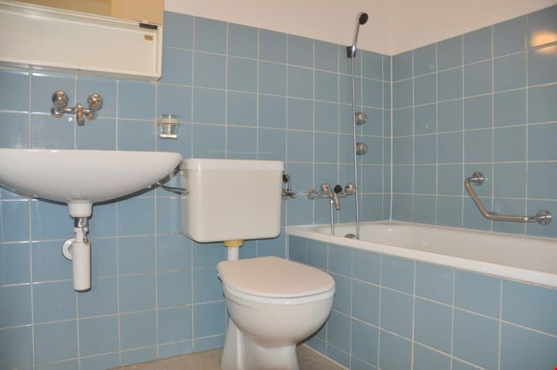 Bathroom with blue tiles, white sink, white toilet, white bathtub, shower head