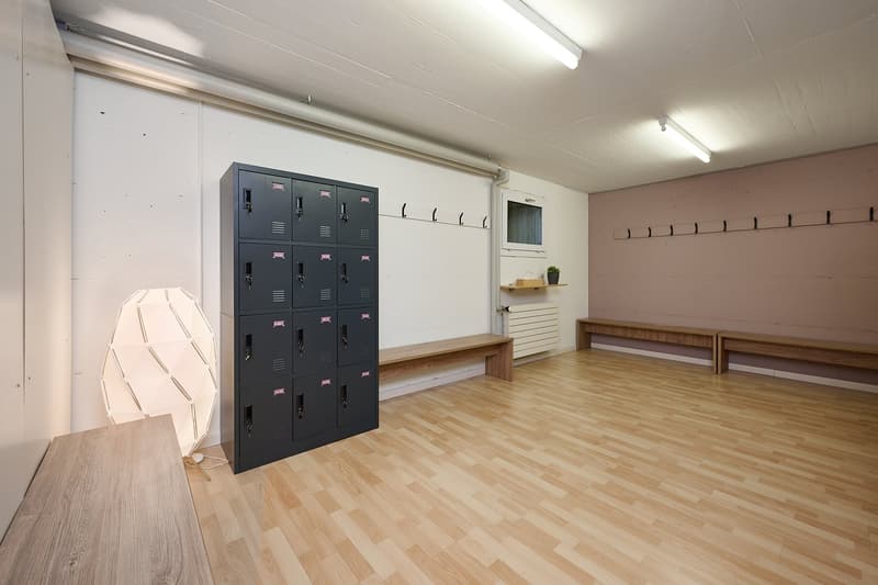 A room with lockers, benches, and a wooden floor