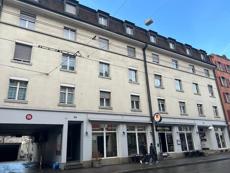 multistory building, large windows, ground floor commercial space, several people walking