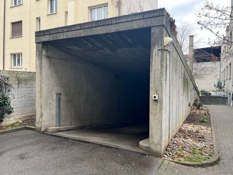 concrete parking structure, open garage, building behind, entrance to street