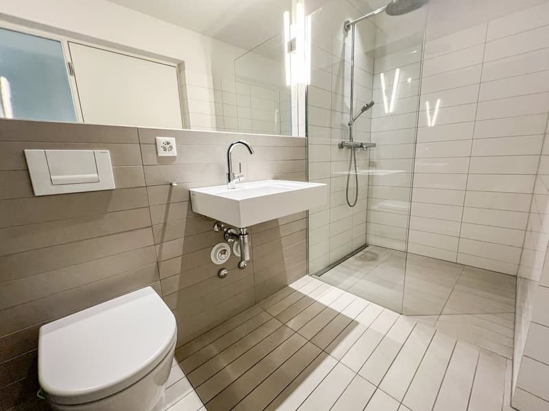modern bathroom with white tiles, glass shower enclosure, white sink, white toilet, mirror