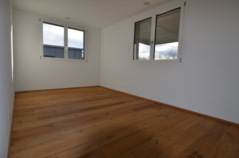 large empty room with hardwood floors and large windows