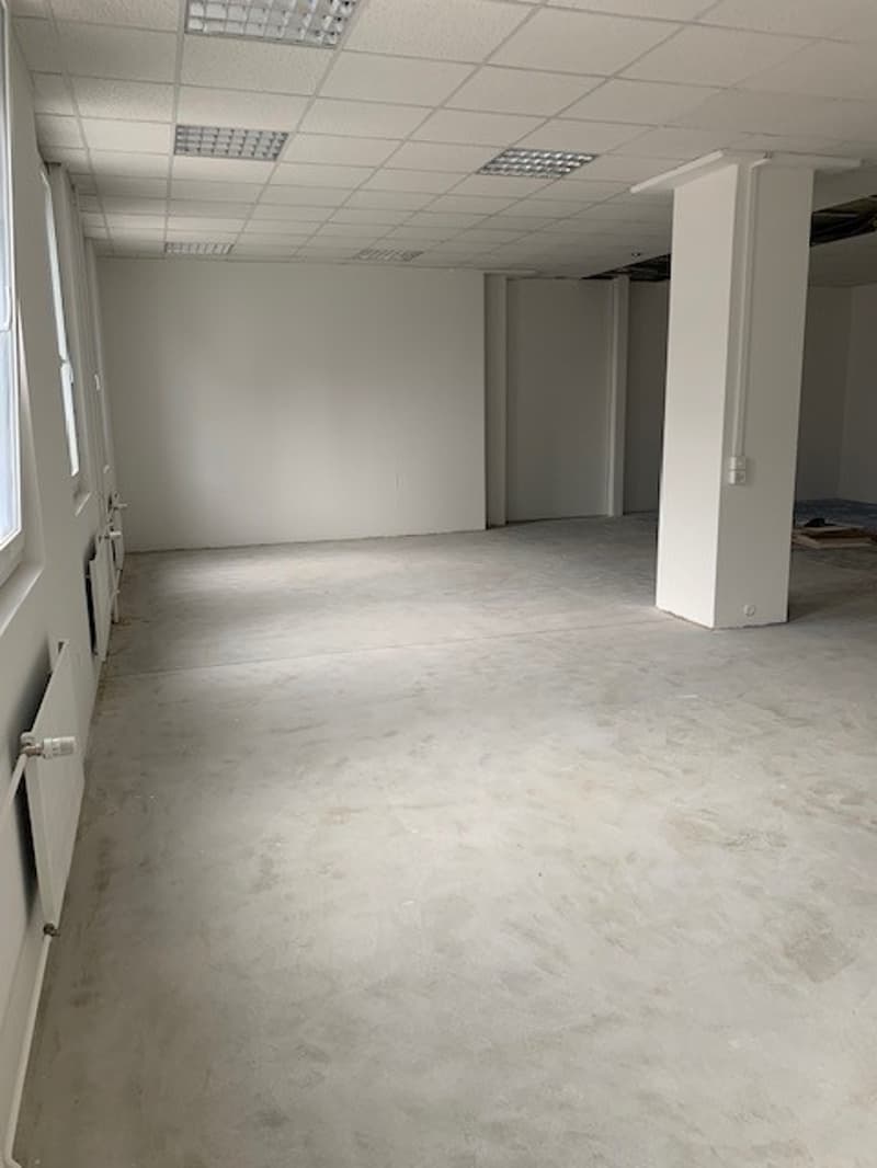 empty room, white walls, concrete floor, windows, pillars