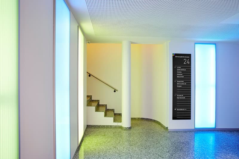 Modern corridor with stairs, granite flooring, vertical lighting panels, a white and yellow wall