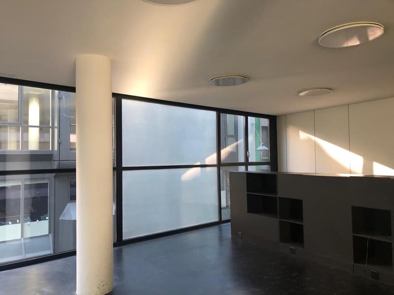 empty room with windows, dark floor, shelves on one side