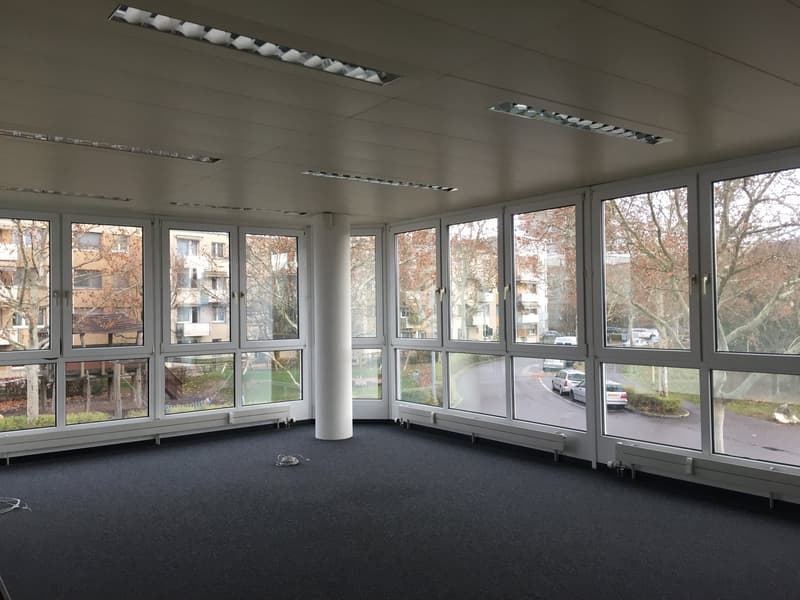 large windows with views of outdoor area, dark carpet, tall pillar in center