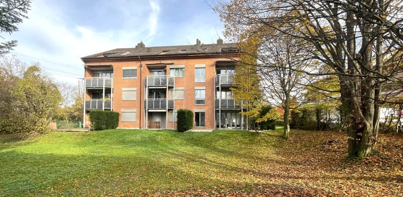 modern apartment building, red brick, large windows, multiple balconies, lawn, trees
