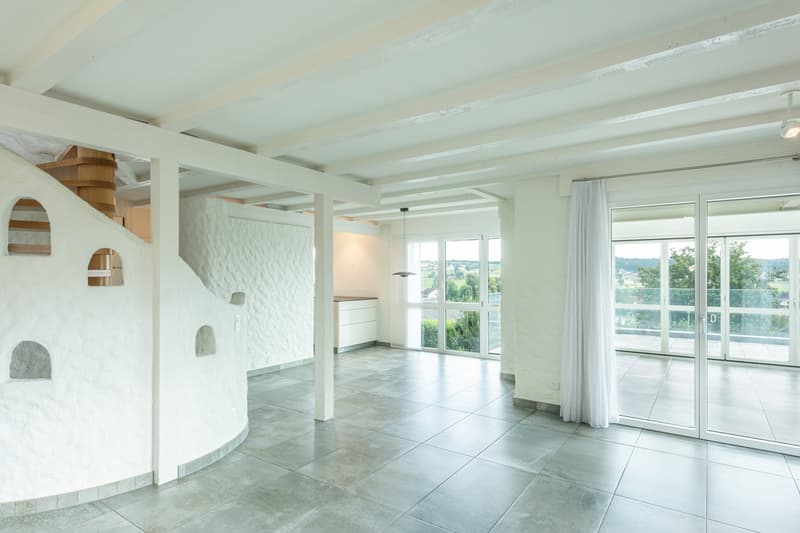 Open plan room with white walls, tile flooring, staircase, balcony, sliding glass doors