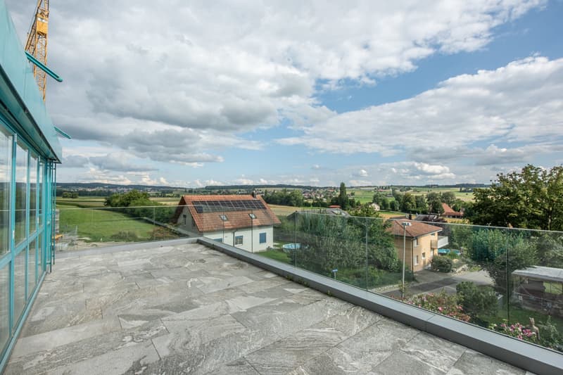 Glass railing, stone floor, view of countryside and buildings