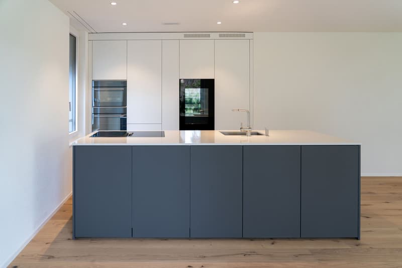 modern kitchen with island, white cabinets, gray countertops, stainless steel appliances, double oven, sink with faucet, wooden floor