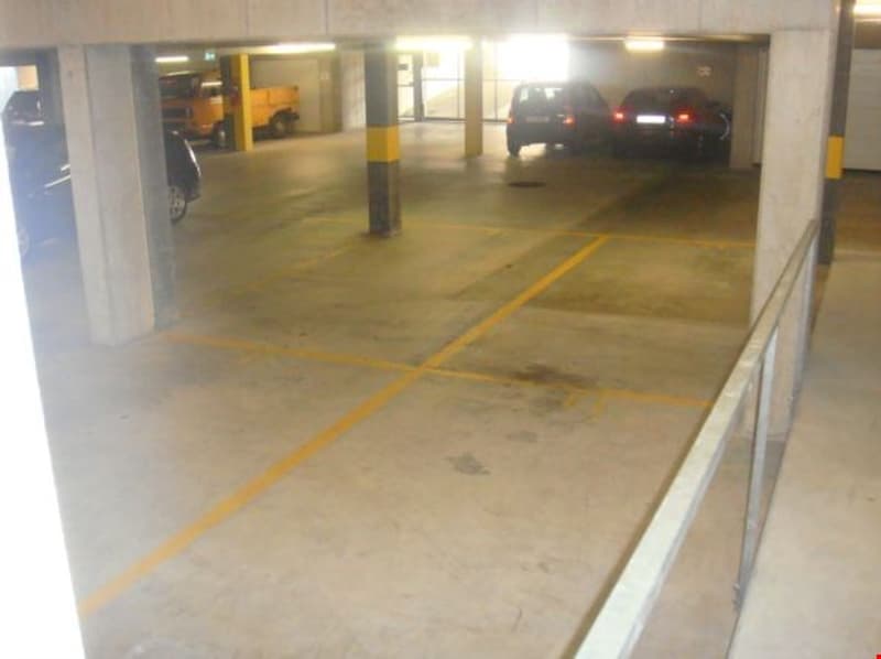 underground parking lot with yellow markings, concrete floor, 3 cars parked