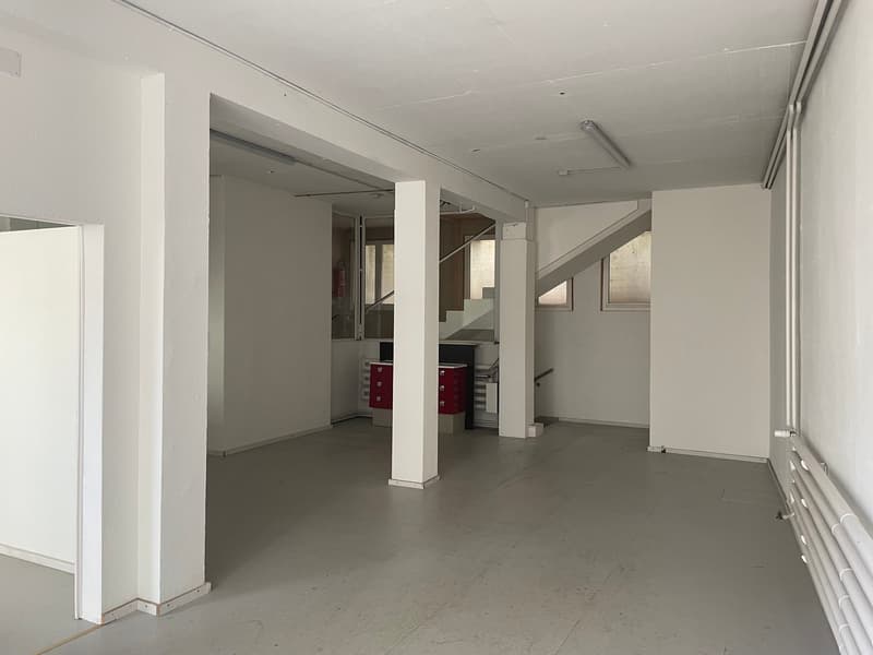 Empty room with white walls, gray floor, two red cabinets, and a staircase.