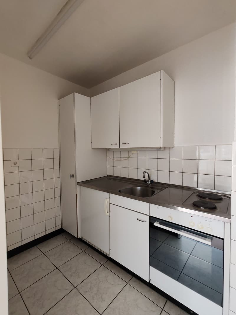Empty modern kitchen with tiled flooring, granite countertop, stainless steel sink, oven, and cabinets.