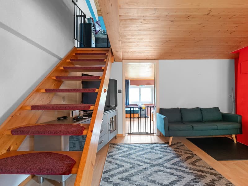 Wooden staircase, living room with sofa, TV, and balcony access