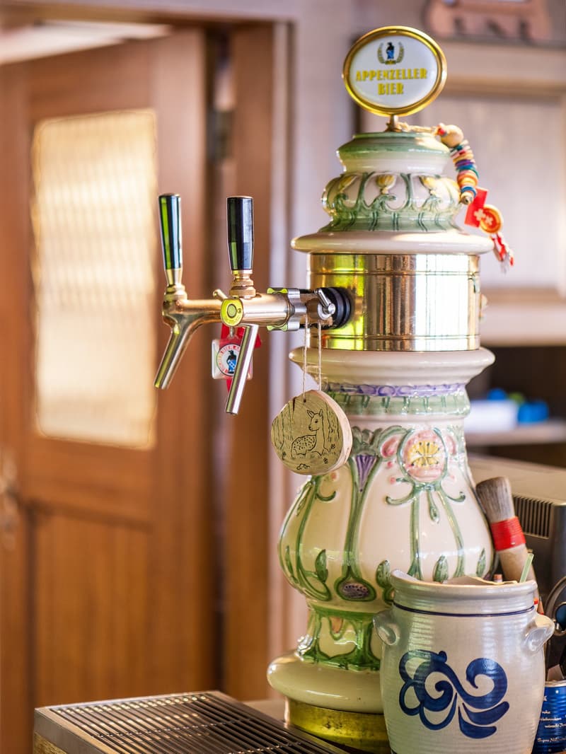 Ornate beer dispenser, kitchen appliances, and decorative items in a cozy, rustic-style kitchen setting.