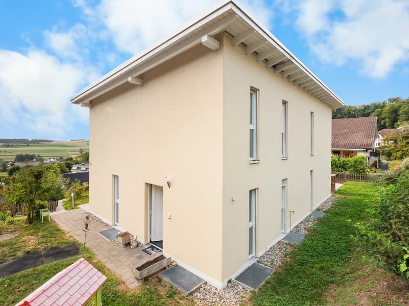 2 story house, beige exterior, white trim, glass windows, raised ground floor, doormat in front
