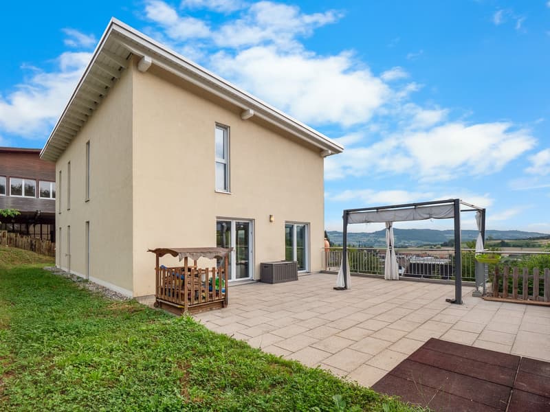 modern house, light beige exterior, patio with pergola, grassy yard, clear sky, storage box