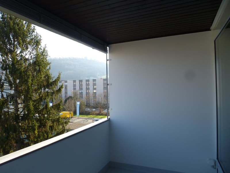 Balcony with railing, view of a large tree and the outside parking area.