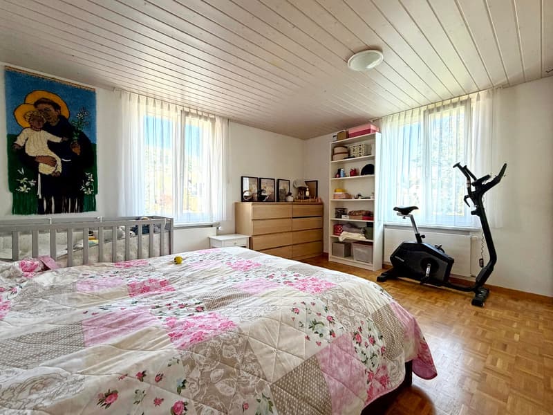 Bedroom with bed, crib, wardrobe, exercise bike, bookshelf, and wall decor