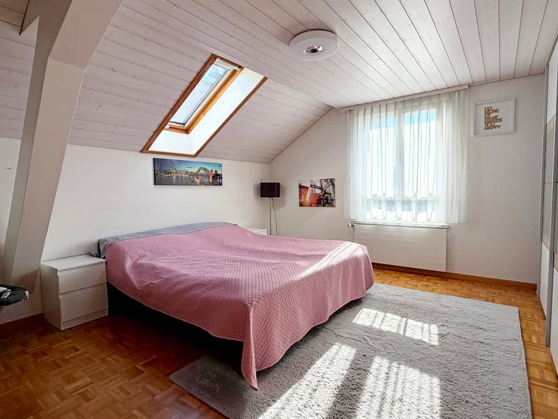 single bed, pink bedspread, white side tables, gray carpet, white ceiling, radiator, skylight