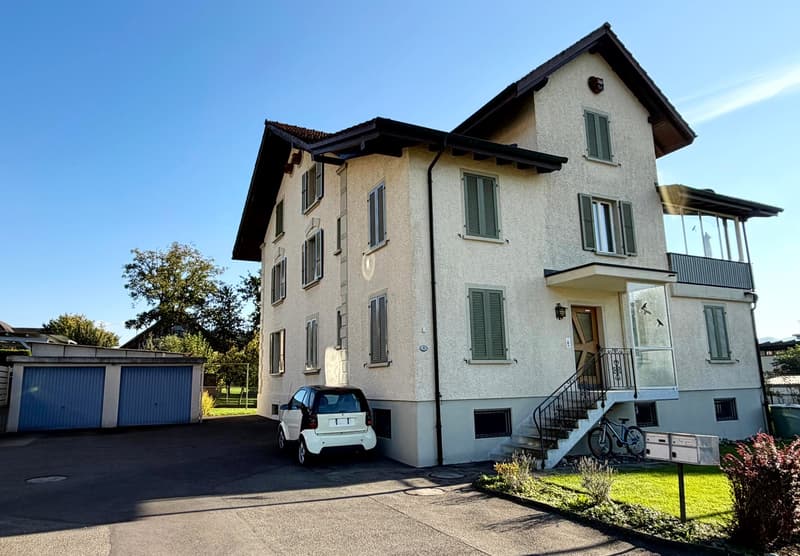 2 story building, white exterior, garage, car parked in front