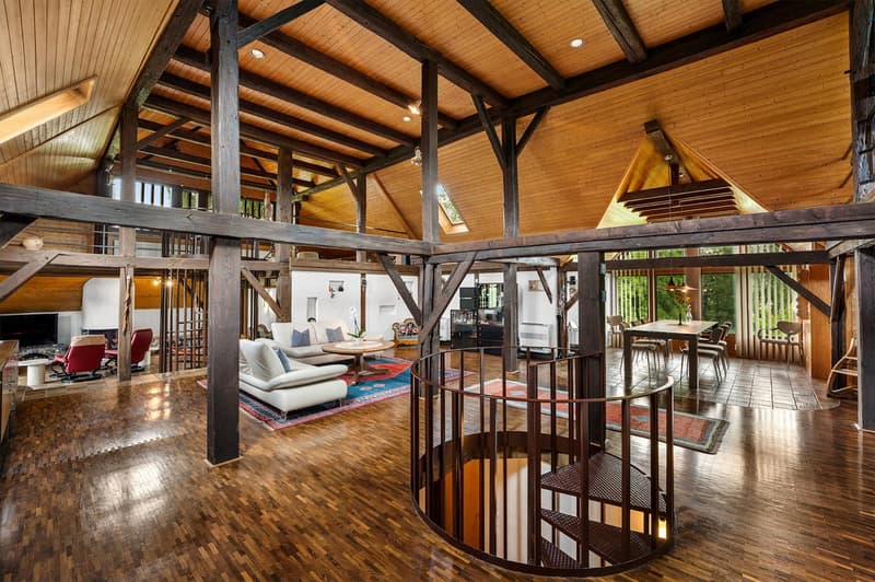 interior with wooden beams, wooden flooring, spiral staircase, couches, armchairs, wooden table, chairs, rug