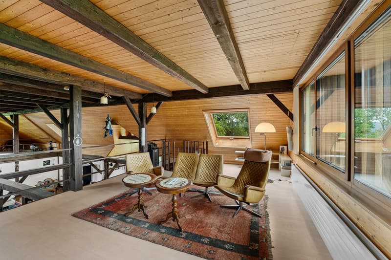 high ceiling, wooden beams, open balcony, large windows, wooden floor, multiple chairs, small tables, rug