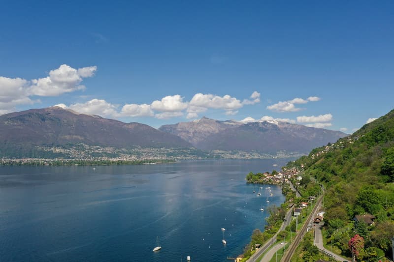 Aerial view of a lake with mountains, a road, and houses