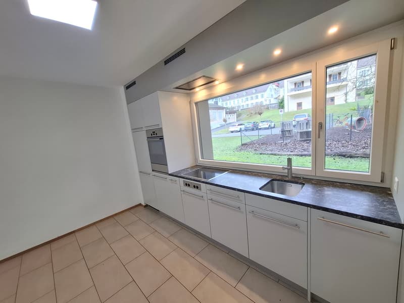 modern kitchen with tile flooring, white cabinets, double stainless steel sink, granite countertop, built-in oven and stove, large windows with view to outdoor area