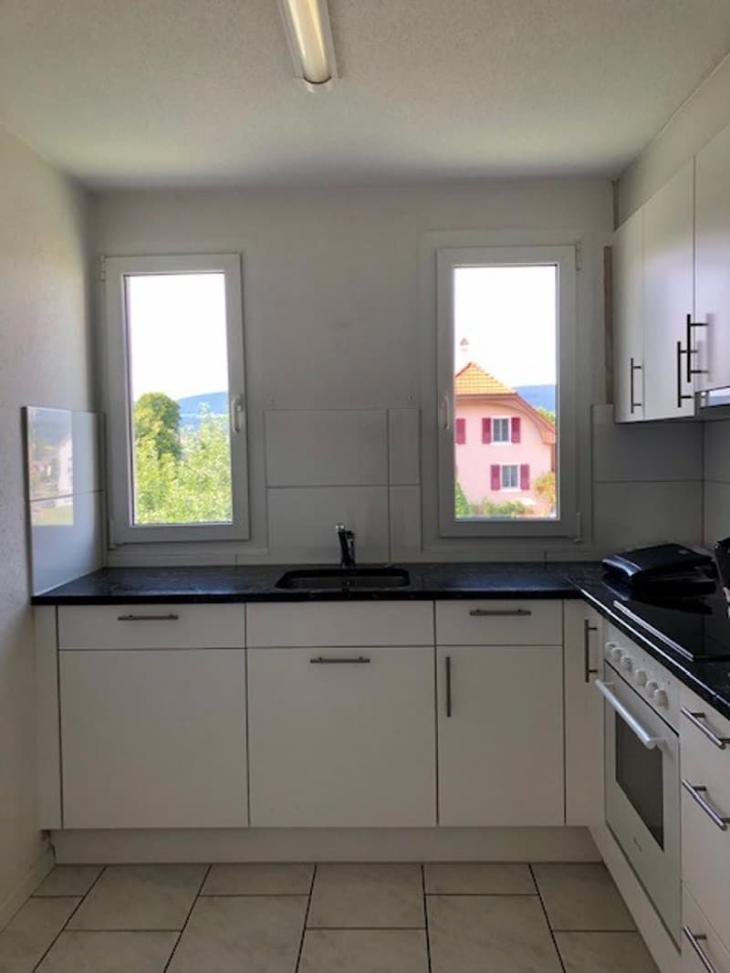 kitchen, tile flooring, white cabinets, black countertops, gas stove, dishwasher, windows