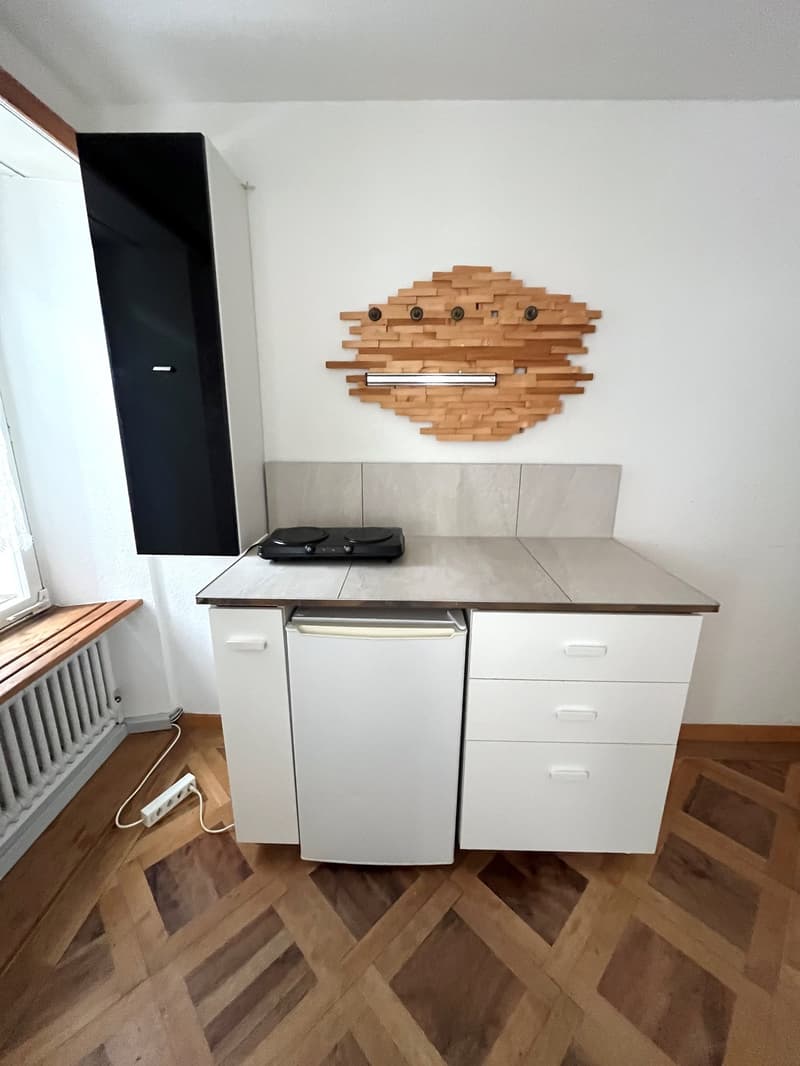 White cabinets, wooden floor, gas stove, wooden decoration on wall, built-in heater