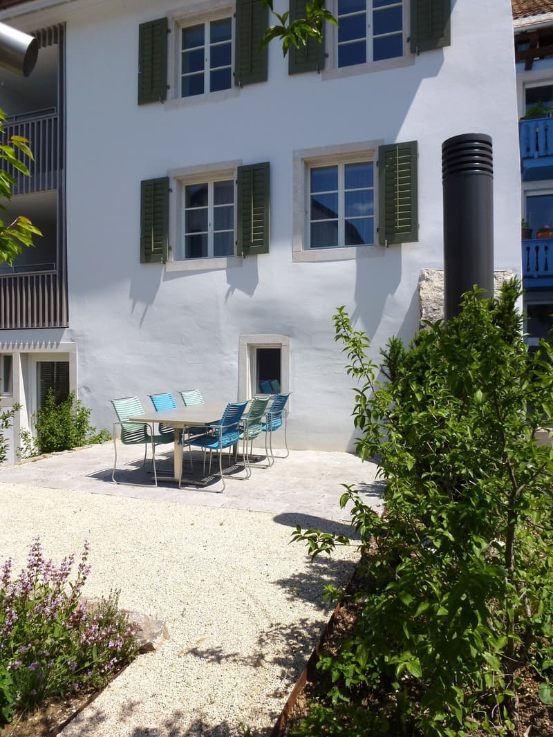 white house, green shutters, table and chairs, gravel patio, plants
