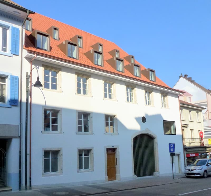 white building, red roof, multiple windows, wooden door, metal gate, street light, parking sign