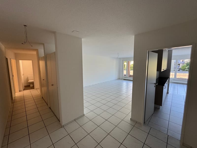Tiled floor, empty room, hallway with closets, entrance to bathroom with toilet