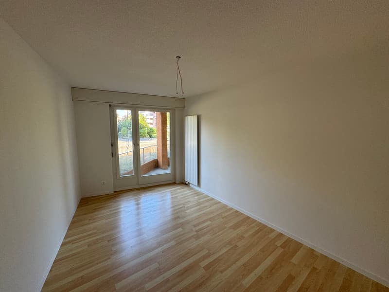 empty room, wooden floor, white walls, sliding glass door leading to a balcony