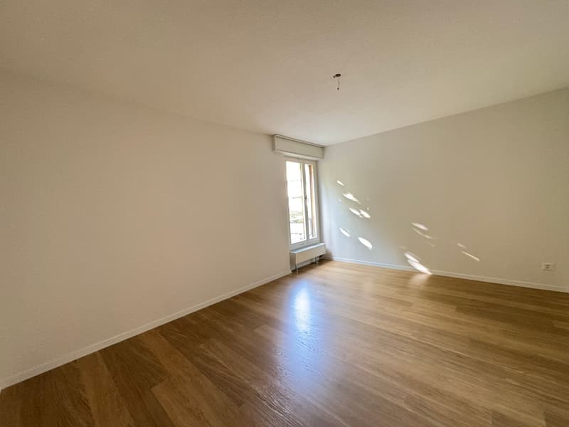 empty room with hardwood floors, white walls, window, radiator