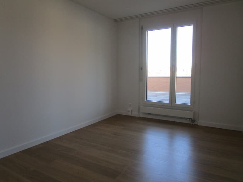 Empty room with wooden floor, white walls, and sliding glass doors