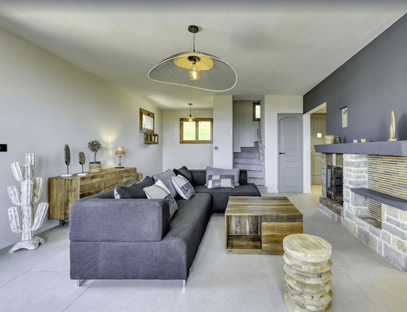 Living room with large sofa, wooden table, gray walls, fireplace, and decorative items